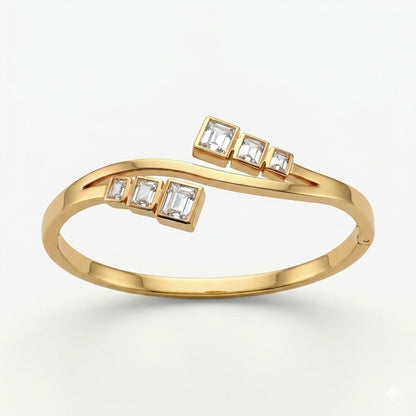 A gold-plated crossover bypass bangle for women featuring graduated baguette-cut crystals and a secure side-clasp.