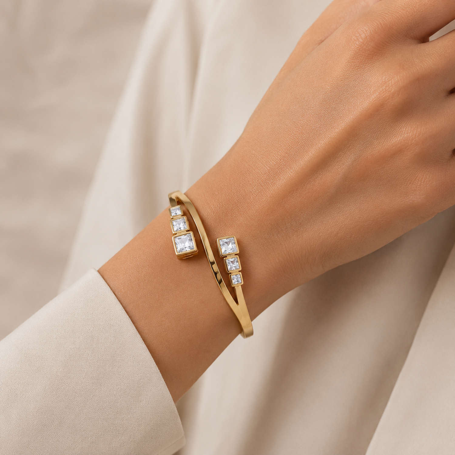 A close-view gold-plated crossover bypass bangle for women featuring graduated baguette-cut crystals and a secure side-clasp, shown on a model