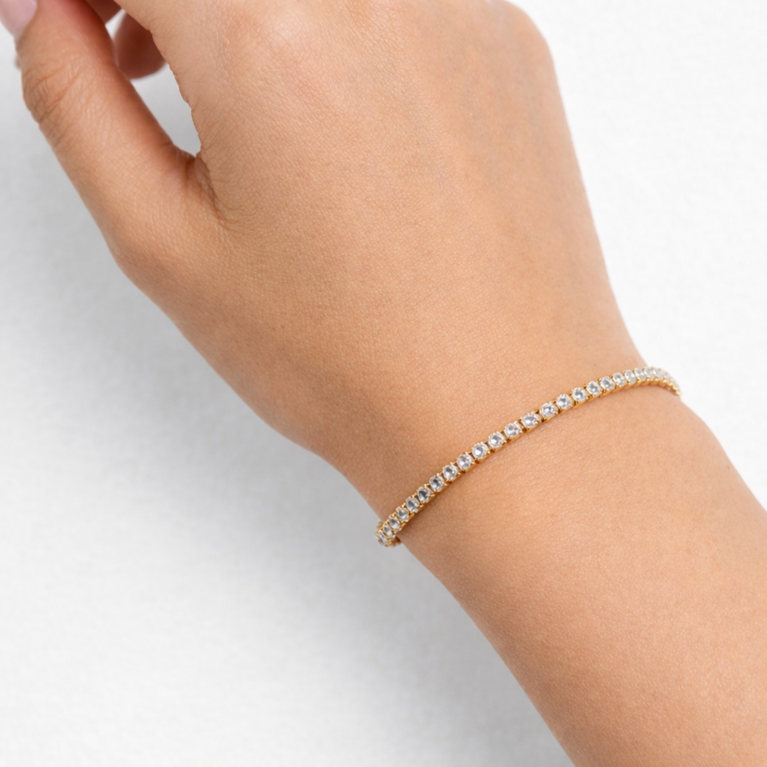 A delicate, thin gold-plated tennis bracelet for women shown on a wrist