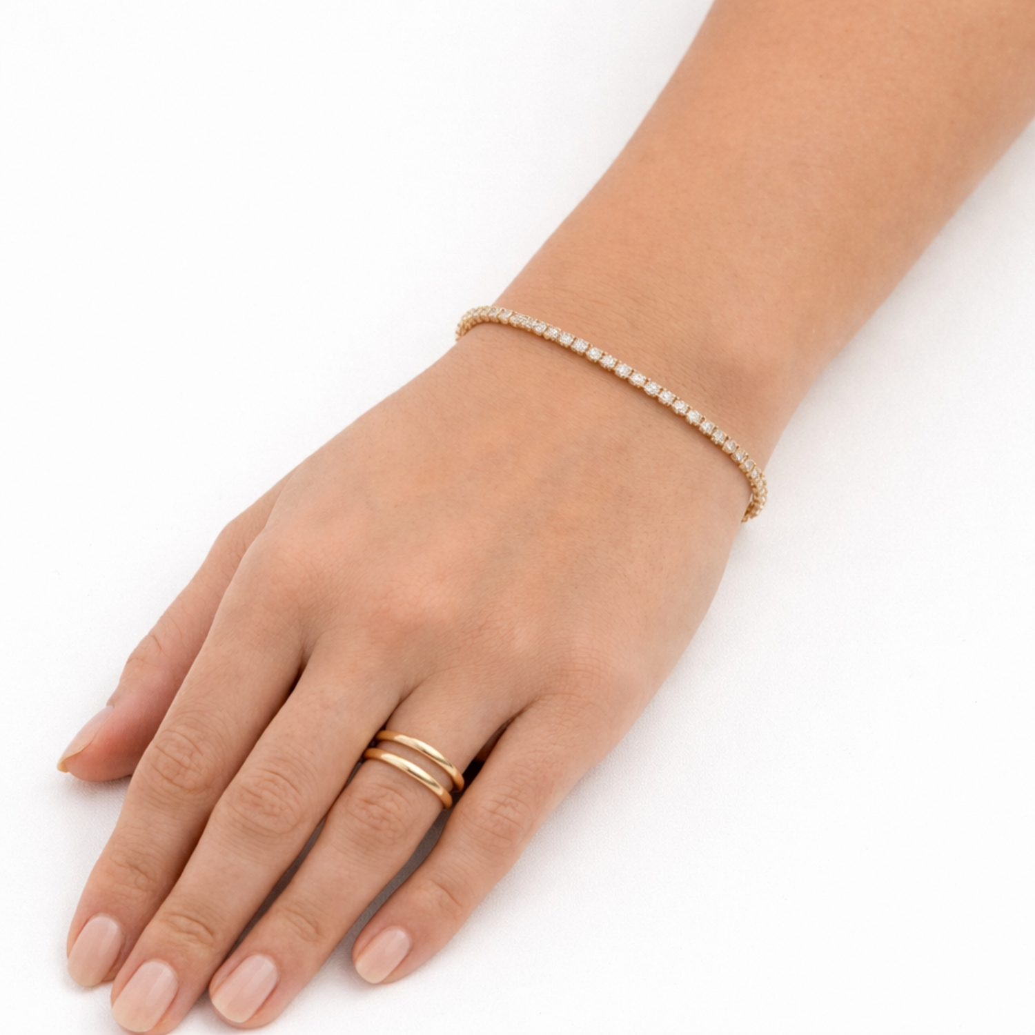 A delicate, thin gold-plated tennis bracelet for women shown on a model hand