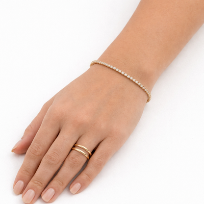 A delicate, thin gold-plated tennis bracelet for women shown on a model hand