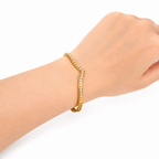 A gold-plated bangle for women featuring an intricate winged design and a secure side clasp, shown on a model
