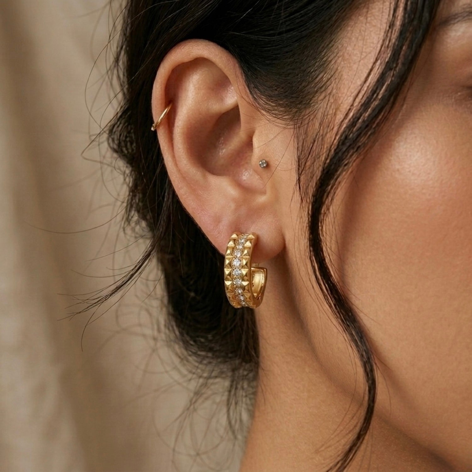 A gold-plated open hoop earrings for women featuring a central row of crystals, shown on a model
