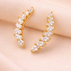 A pair of of gold-plated celestial Zenith Starburst ear climber earrings for women featuring stones and a star motif on a beige background
