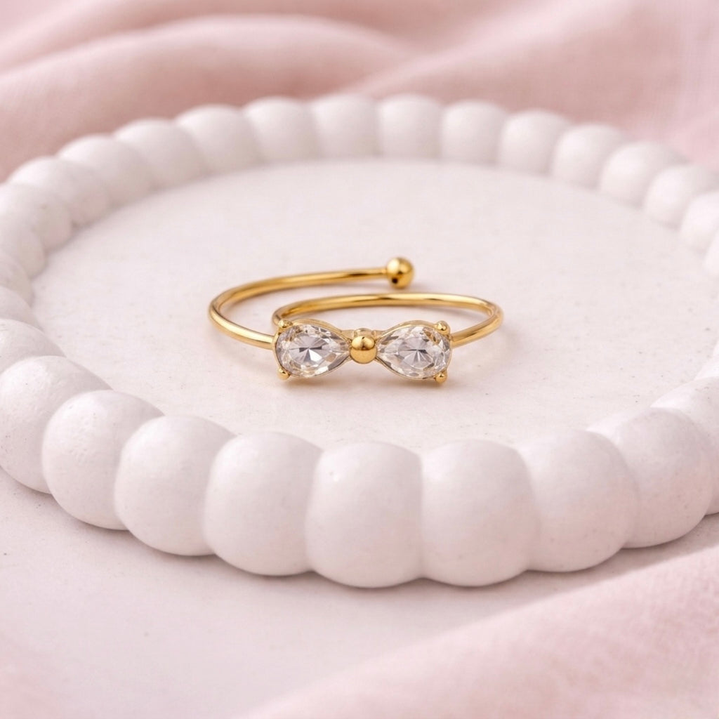 A dainty gold plated adjustable ring for women featuring a bow design shown on a white surface