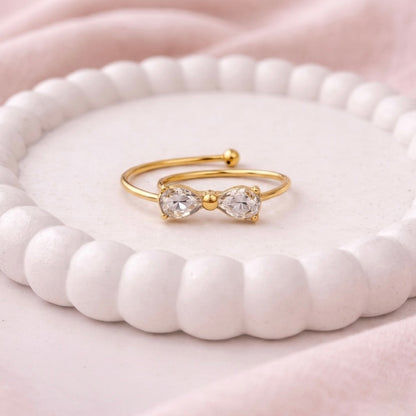 A dainty gold plated adjustable ring for women featuring a bow design shown on a white surface